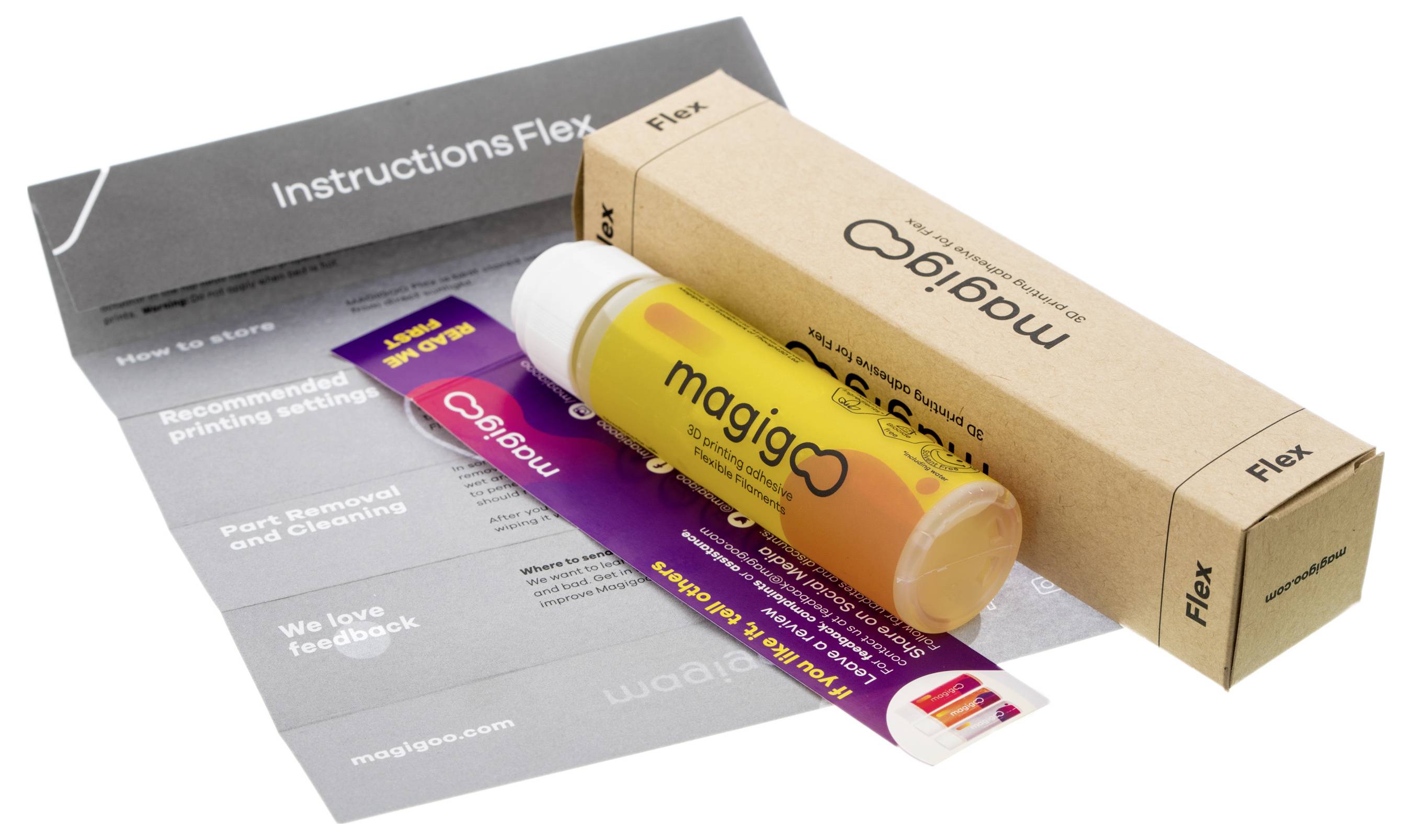 Magigoo Flex Bastelklebstoff auf grauem und lilafarbenem Verpackungspapier mit Anleitung zum Gebrauch und Karton.