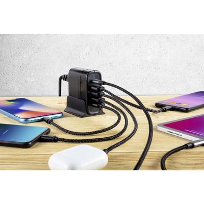 Mehrere Smartphones sind an einem Mehrfach-USB-Ladegerät auf einem Holztisch angeschlossen.