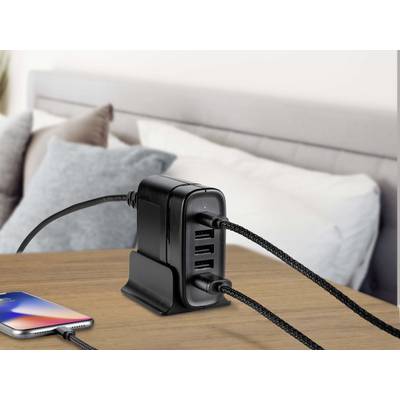 Ein Mehrfach-USB-Ladegerät mit vier Anschlüssen steht auf einem Holztisch. Zwei Geräte sind angeschlossen, darunter ein Smartphone.