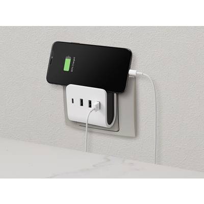 Smartphone lädt am Ladegerät in einer Steckdose. Der Akku zeigt eine grüne Ladestandanzeige. Drei USB-Ports am Ladegerät verfügbar.