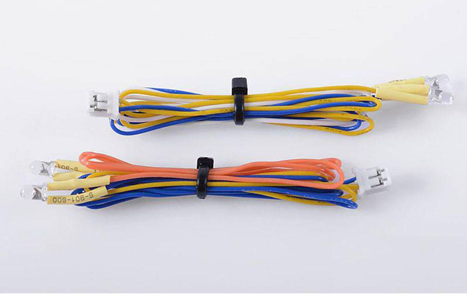 Zwei Bündel farbige Kabel mit Steckverbindern, gelb, blau und rot, horizontal auf weißem Hintergrund nebeneinander platziert.