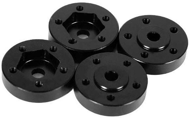 Vier schwarze Metallkomponenten mit Löchern, symmetrisch angeordnet. Sie scheinen Teil eines mechanischen Systems zu sein.