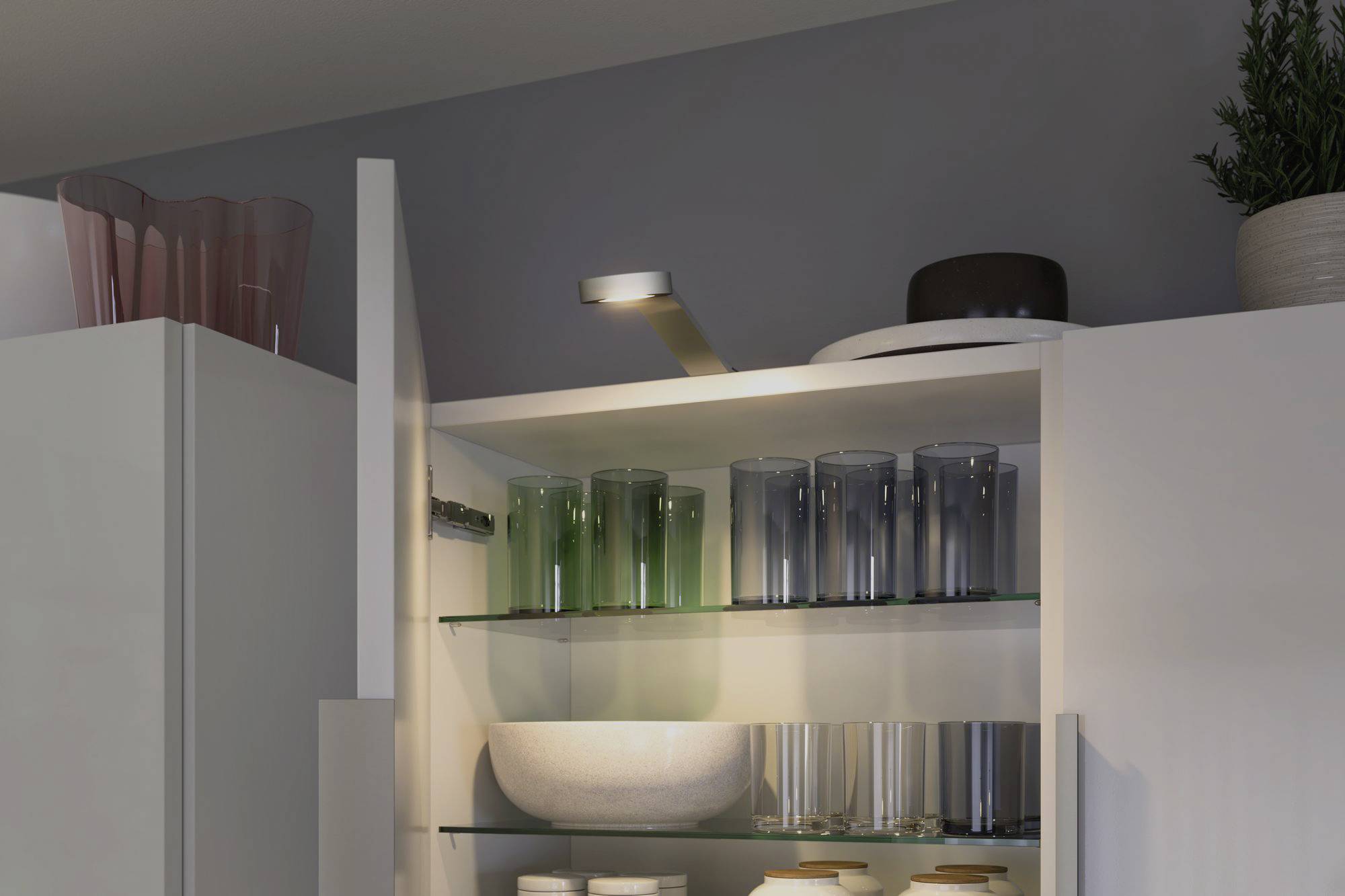 Ein offener Küchenschrank zeigt Gläser, Schalen und einen Teller, beleuchtet von einem eingebauten Licht oben im Schrank.