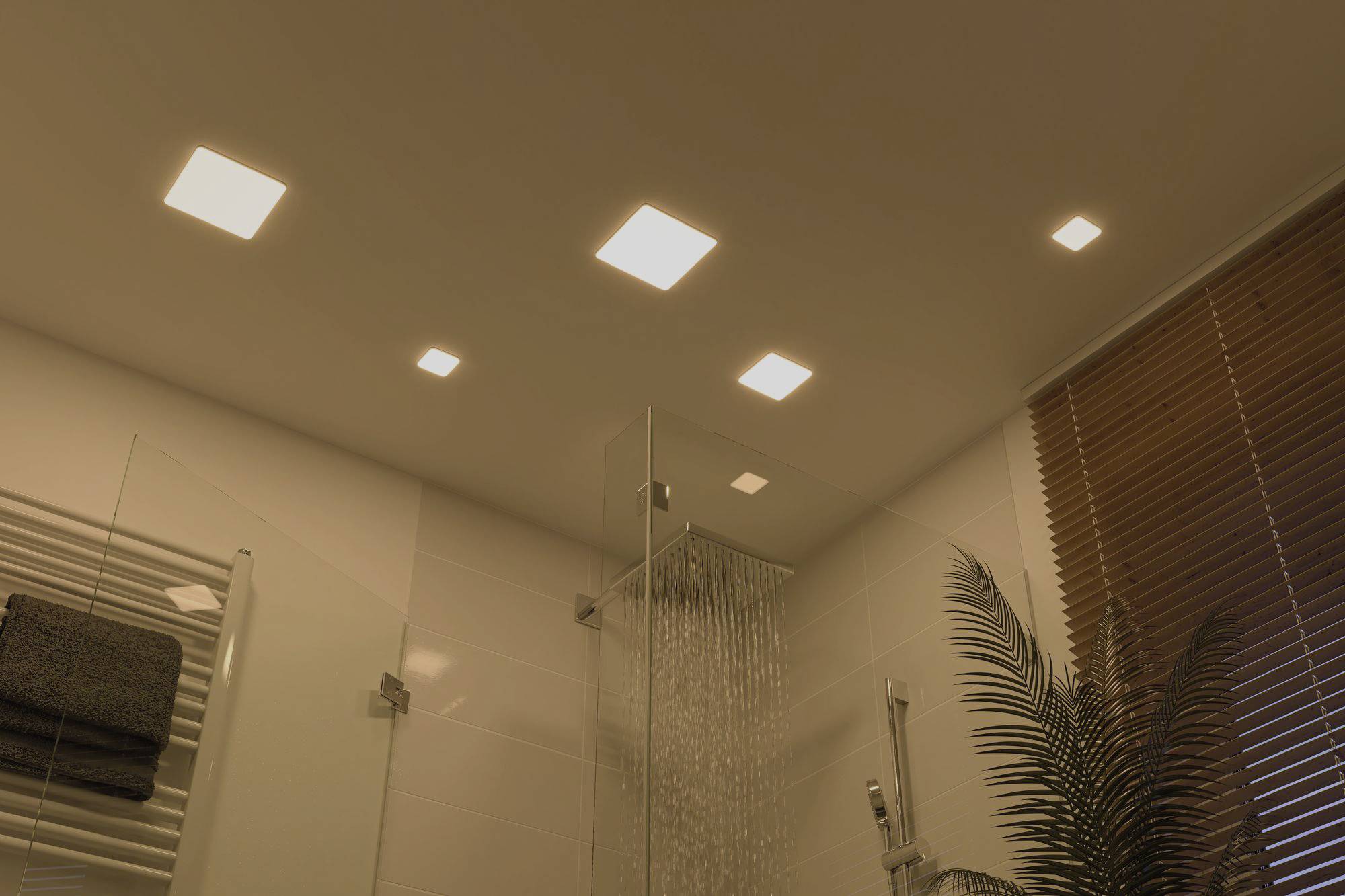 Moderne Badezimmerdecke mit fünf quadratischen Deckenleuchten. Dusche mit Glaswand links im Bild. Rechts Holzjalousien und Pflanze.