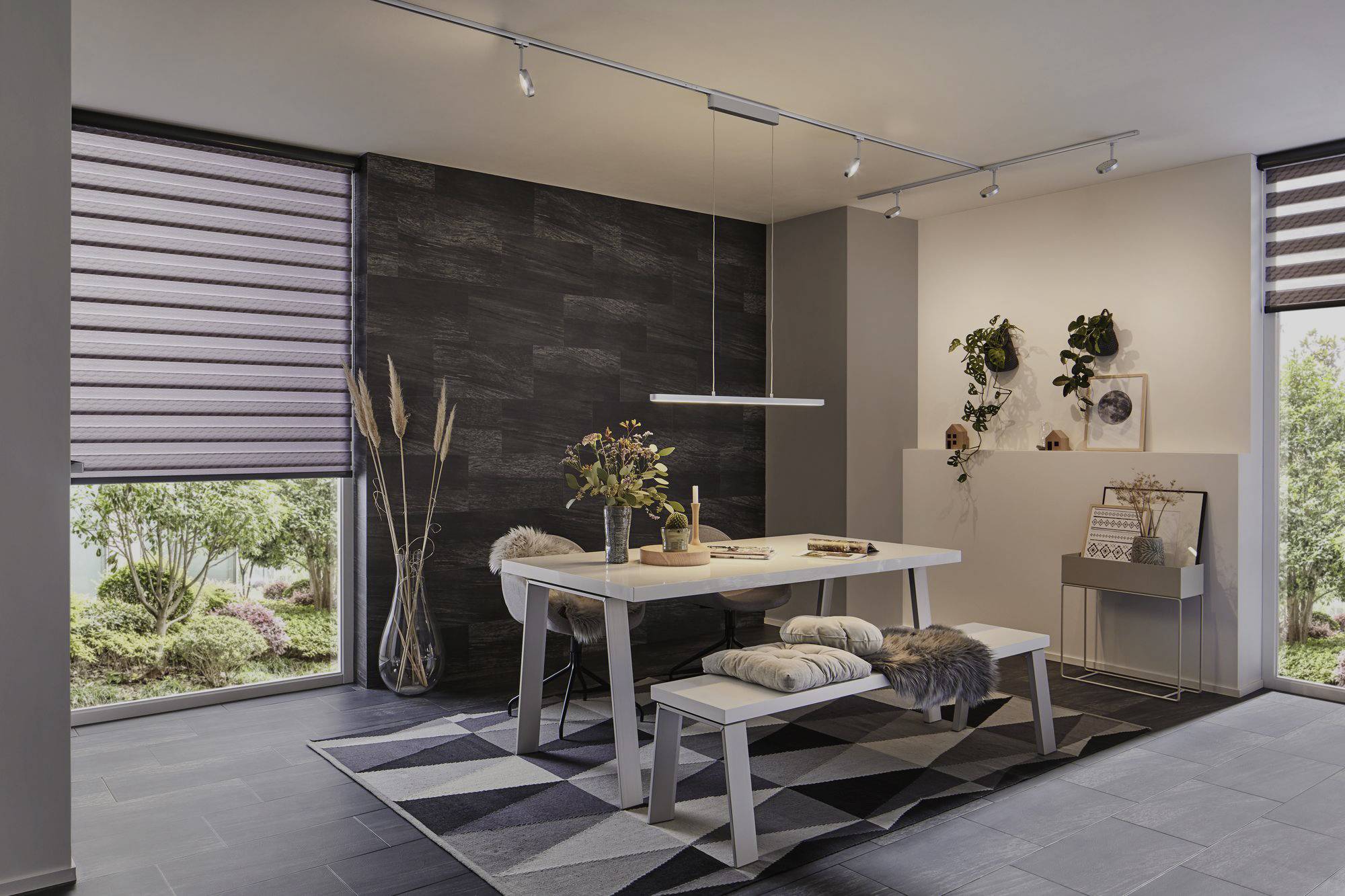 Esszimmer mit modernem Tisch, Bank und Stühlen. Pflanzen und Dekoration im Hintergrund, große Fenster mit Sicht auf Garten.