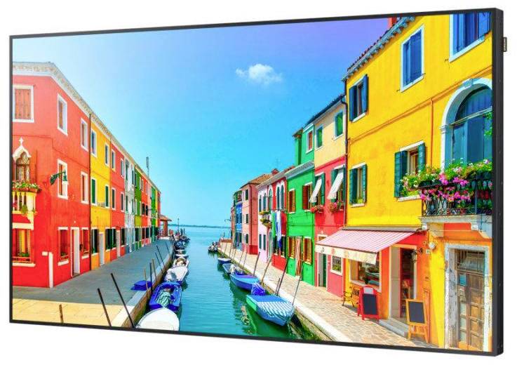 Häuser mit bunten Fassaden an einem Kanal. Boote liegen am Wasser. Der Himmel ist klar. Lebendige und fröhliche Szenerie.