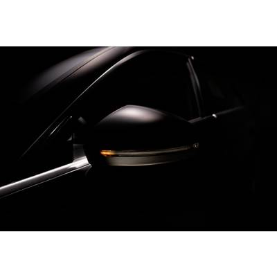 Nahaufnahme eines dunkel beleuchteten Auto-Seitenspiegels mit eingeschaltetem Blinker, der ein orangenes Licht ausstrahlt.
