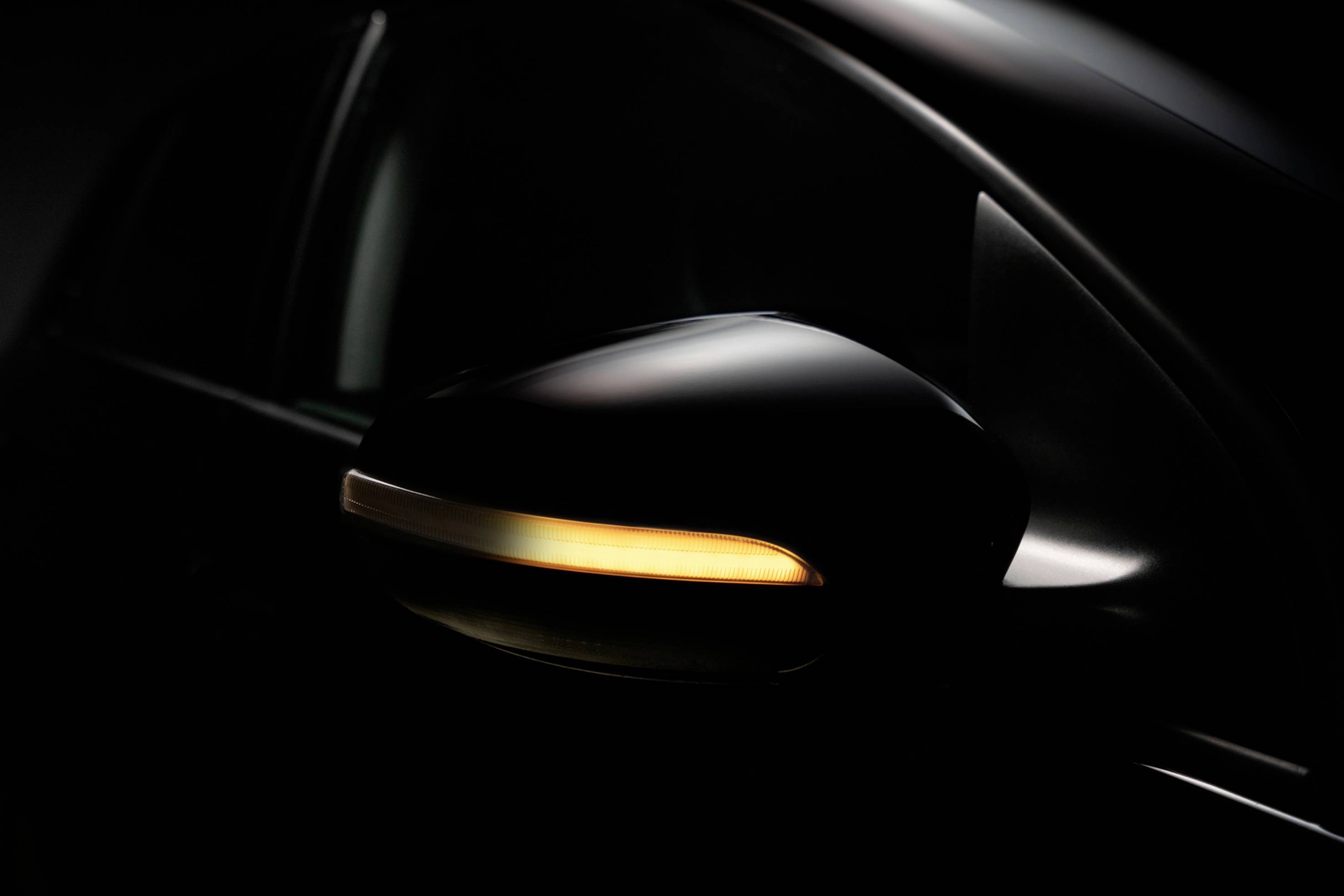 Seitenspiegel eines Autos mit eingeschaltetem Blinker, der einen gelben Lichtstreifen erzeugt.