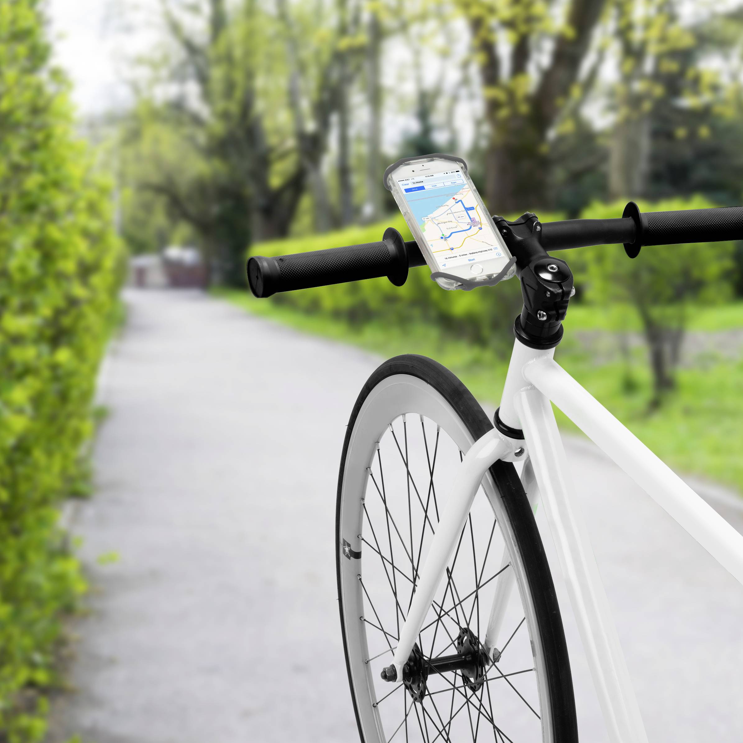 Ein Fahrrad steht auf einem Waldweg, dessen Lenker mit einem Smartphone mit geöffneter Navigations-App ausgestattet ist.