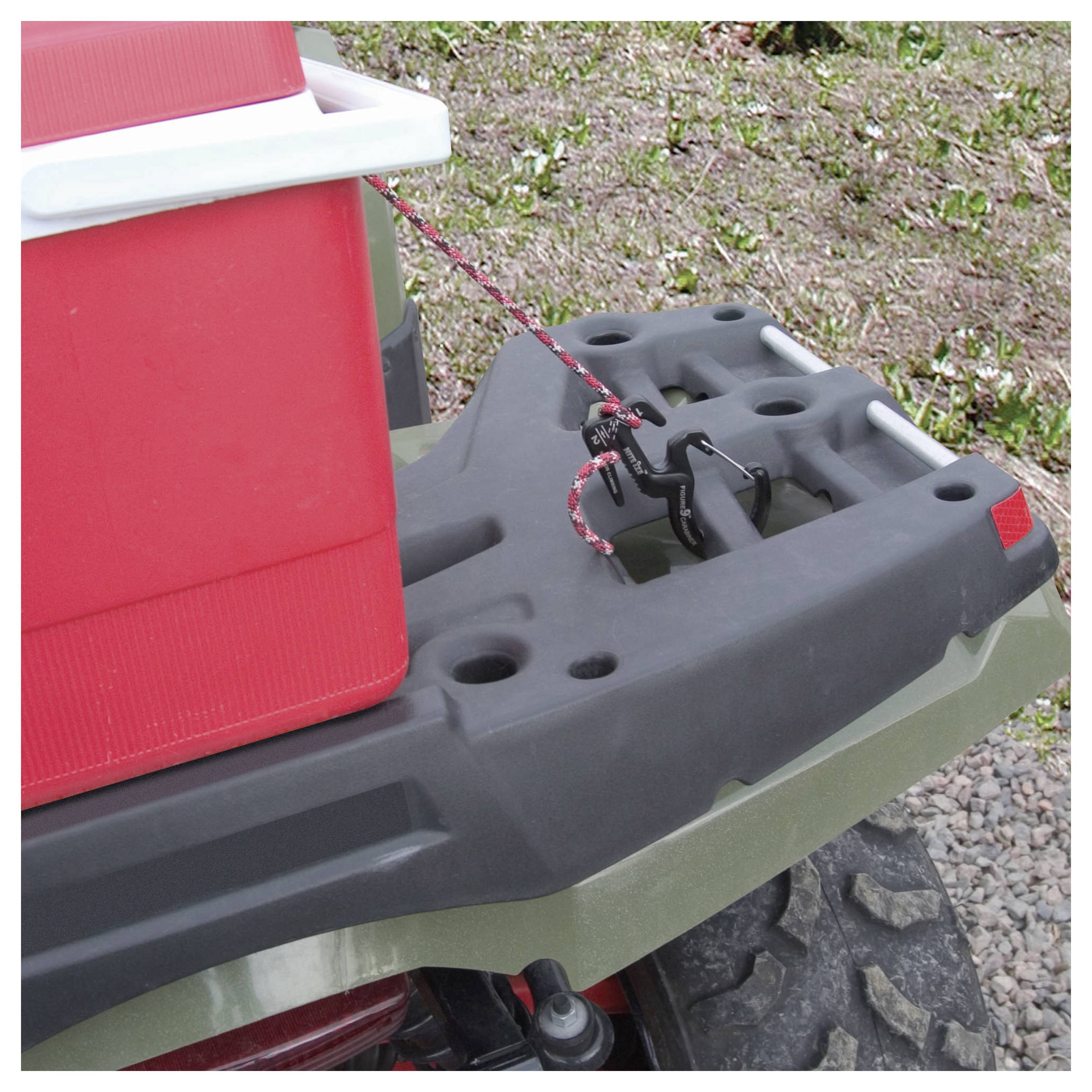 Ein roter Kühlschrank, der mit einem Spanngurt auf der Rückseite eines ATVs befestigt ist, geparkt auf Gras und Kies.