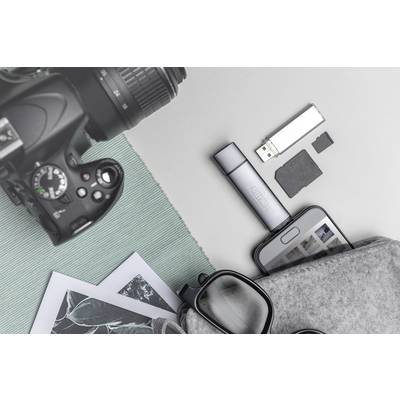 Kamera, USB-Stick, Smartphone, Brille und Fotos auf grauem Untergrund; repräsentiert digitale und analoge Fotografie.