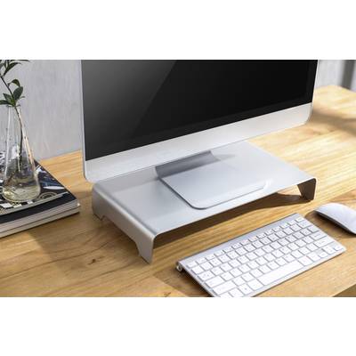 Ein Computerbildschirm auf einem weißen Standfuß, mit Tastatur und Maus auf einem Holztisch. Im Hintergrund sind Bücher und eine Vase.