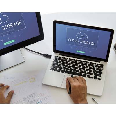 Zwei Bildschirme zeigen 'Cloud Storage', daneben schreibt eine Person auf Notizblätter. Thema: digitale Speicherung und Datenmanagement.