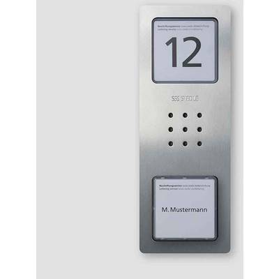 'SSS Siedle' Klingelsystem mit Nummer '12' und Name 'M. Mustermann'. Silberne Oberfläche mit zwei Beschriftungsbereichen und Lautsprecher.