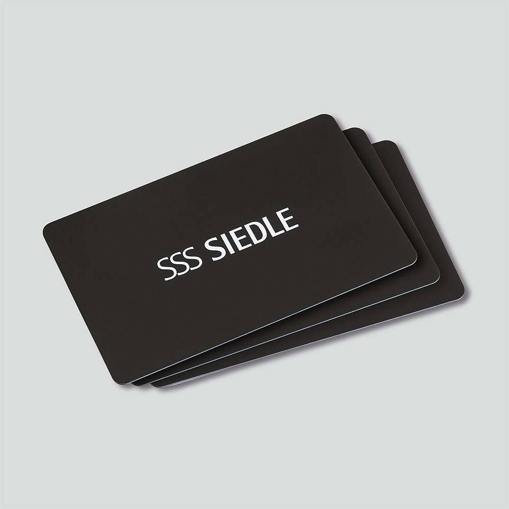 Drei schwarze Karten mit dem weißen Logo 'SSS Siedle' auf einer grauen Oberfläche.