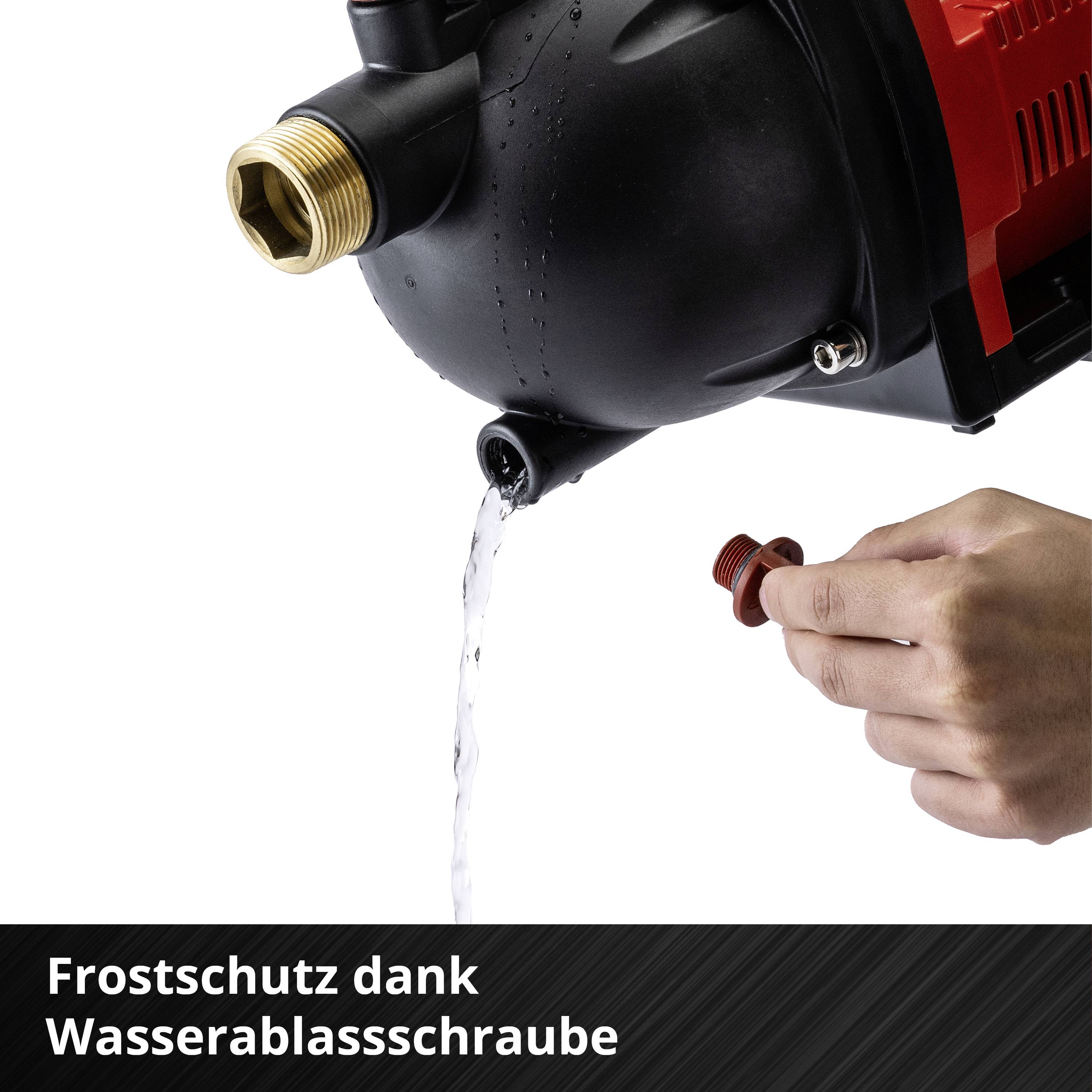 Ein rotes Gerät mit einem Wasserablassschraube für Frostschutz. Eine Hand dreht die Schraube, aus der ein Wasserstrahl fließt.