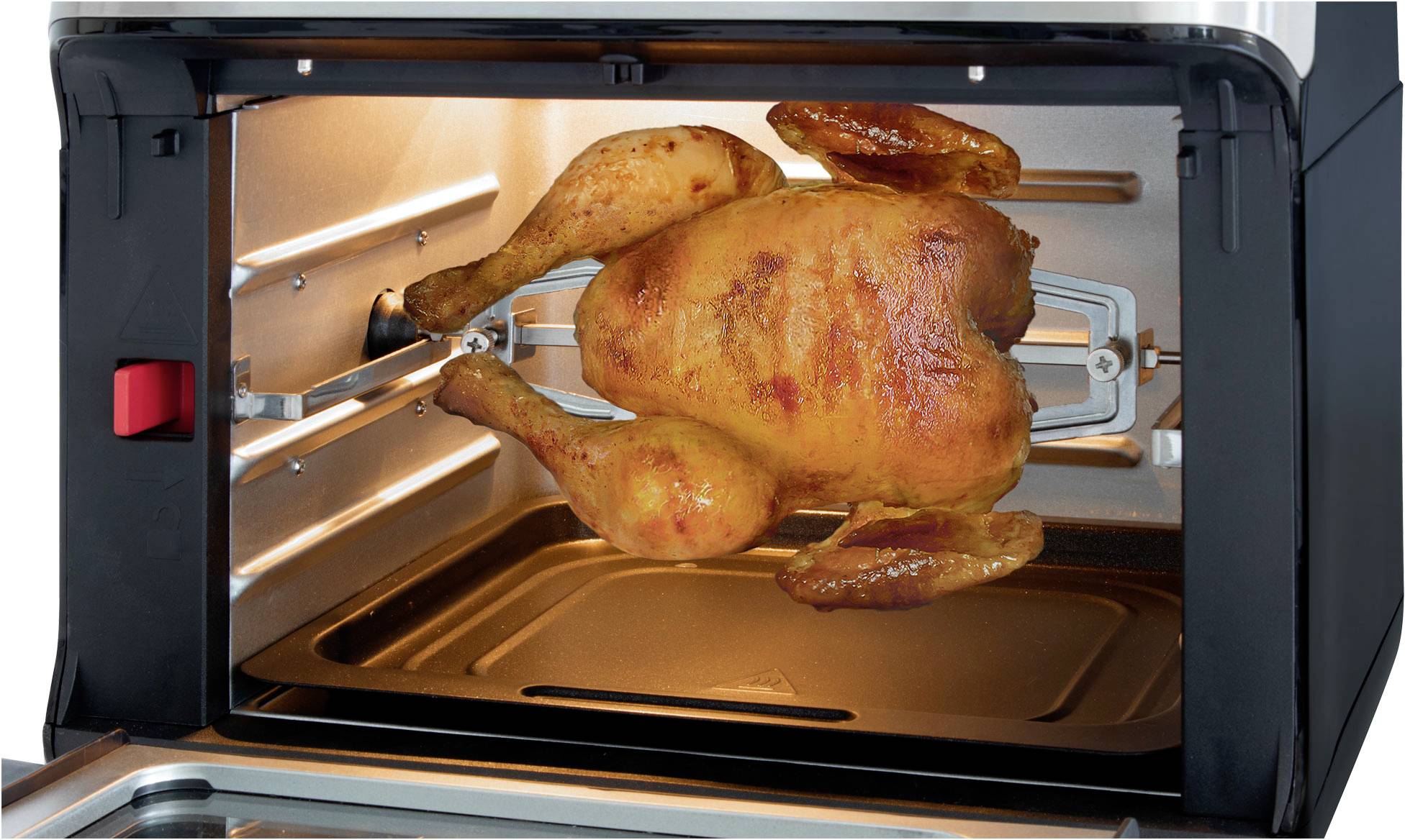 Ein ganzes Brathähnchen wird in einem Ofen auf einem Drehspieß gegrillt; es ist knusprig braun gebraten.