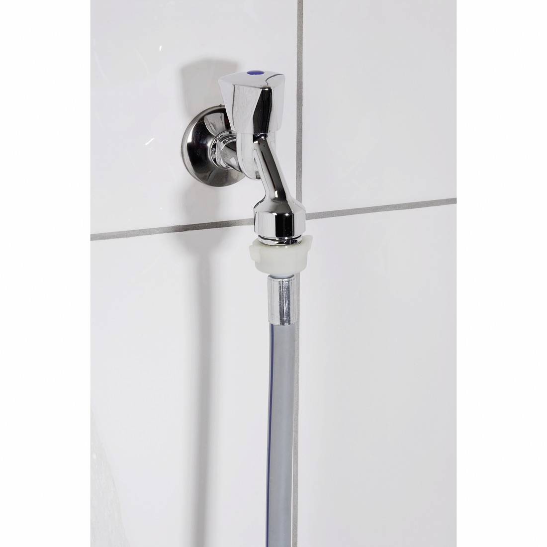 Ein Wasserhahn mit angeschlossenem flexiblen Schlauch vor einer weißen gefliesten Wand.