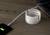 Ein Laptop wird über ein USB-Kabel mit einem weißen, aufgerollten Spiralkabel an einer Powerbank auf einem Holztisch aufgeladen.