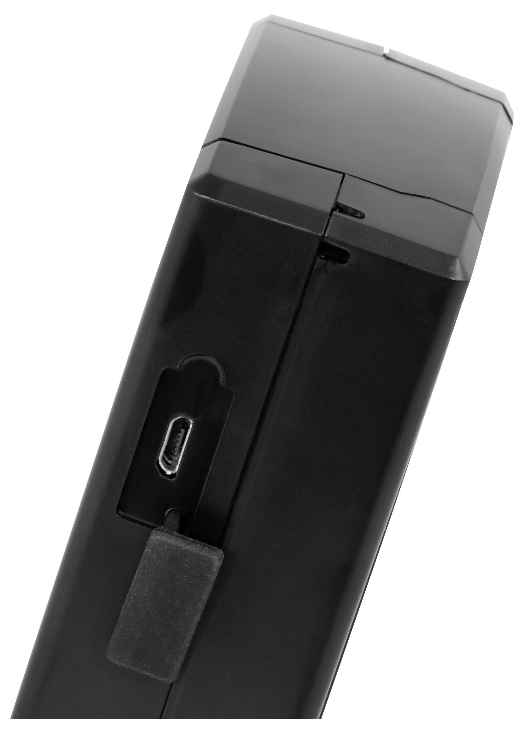 Nahaufnahme eines schwarzen elektronischen Geräts, das einen Micro-USB-Ladeanschluss zeigt, der von einer kleinen Klappe abgedeckt ist.