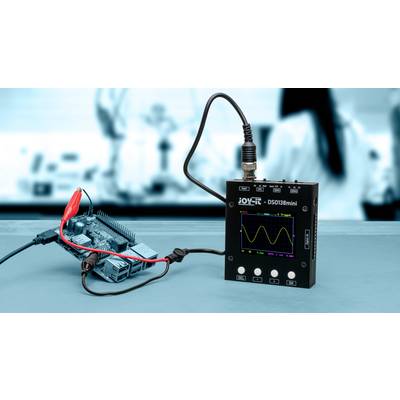 'Oszilloskop DS0138mini' zeigt Sinuskurve auf Display, verbunden mit Mikrocontrollerplatine über rote und schwarze Kabel. Im Laborhintergrund.