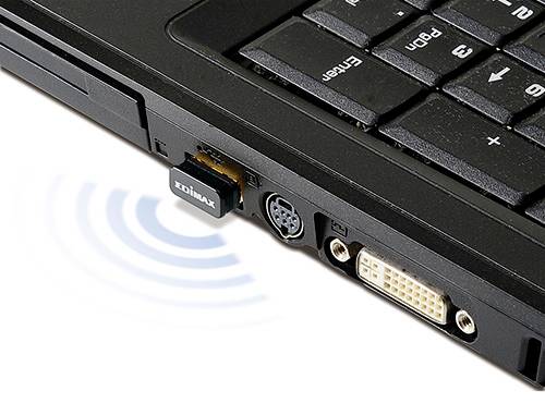 Nahaufnahme eines schwarzen Laptops mit einem WLAN-Adapter im USB-Port. Wellenlinien symbolisieren eine drahtlose Verbindung.