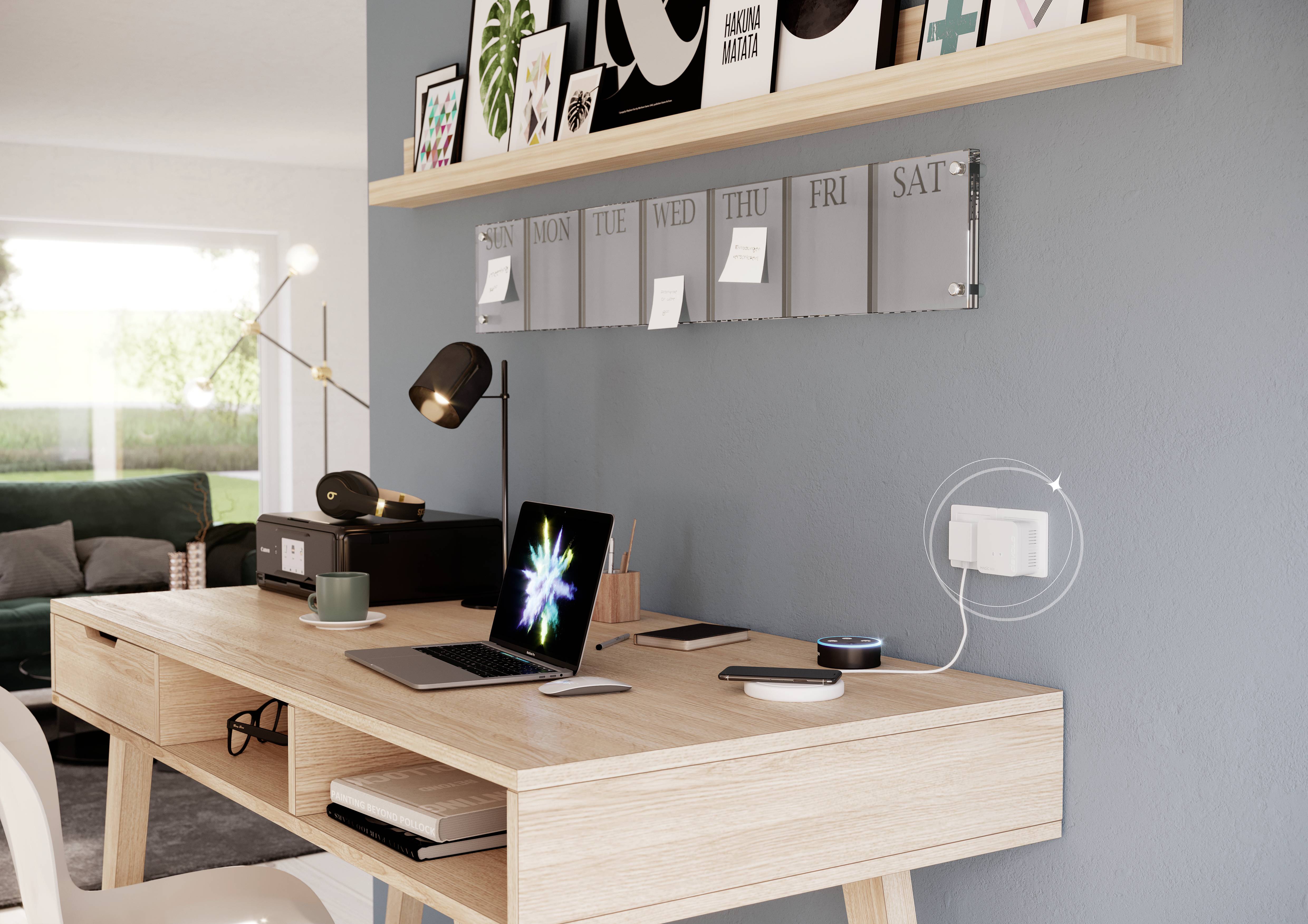 Ein aufgeräumter Schreibtisch mit Laptop, Lampe und Deko. An der Wand ein Wochenplaner und Regale mit Büchern und Bildern in einem Wohnzimmer.