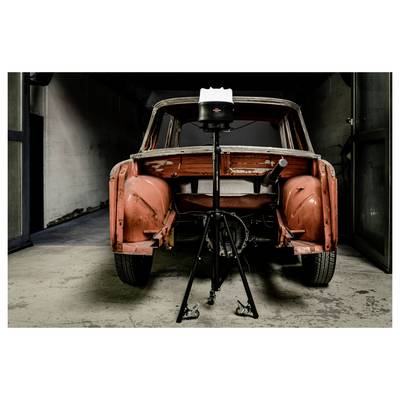 Frontansicht einer abgestreiften orangefarbenen Vintage-Autokarosserie auf einem Stativständer in einer Garage, die laufende Restaurierungsarbeiten zeigt.