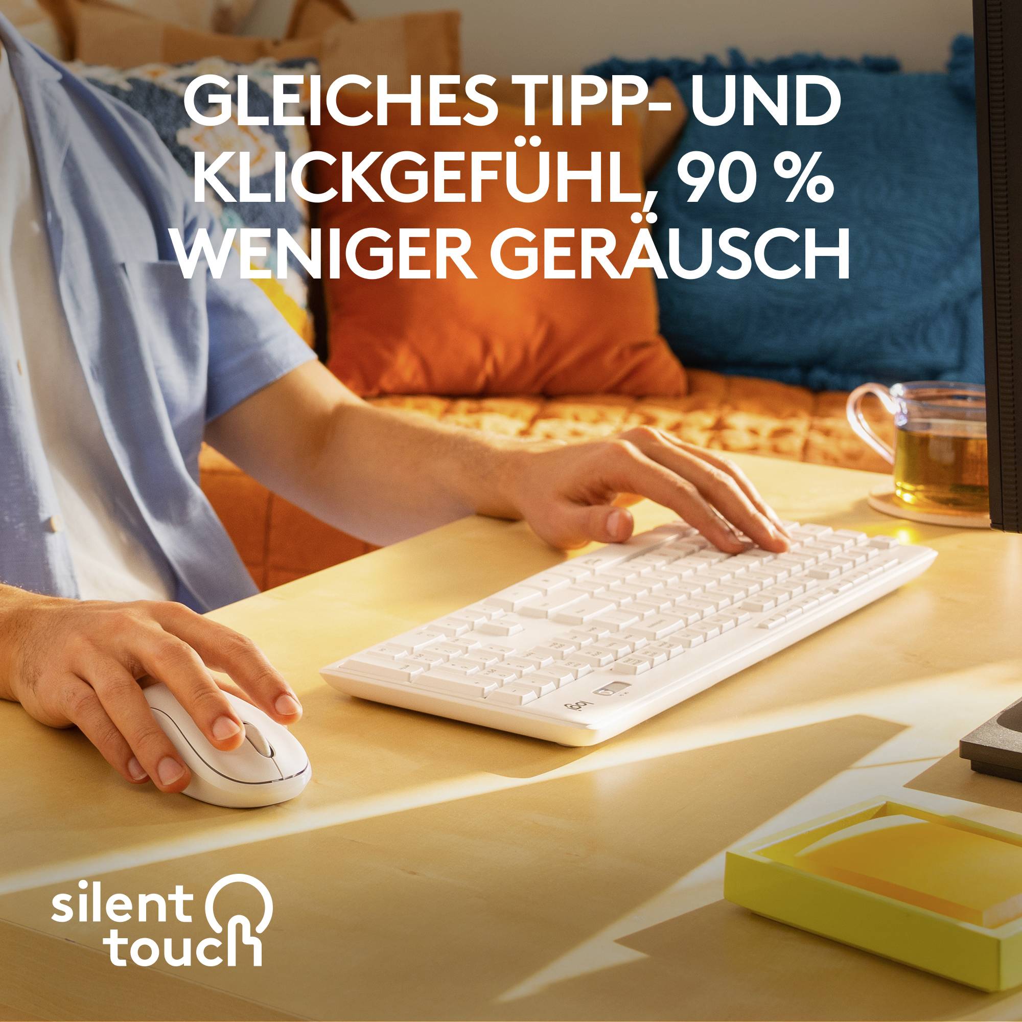 Ein Mensch arbeitet an einem Computer mit einer weißen Tastatur. Text: 'Gleiches Tipp- und Klickgefühl, 90 % weniger Geräusch.'