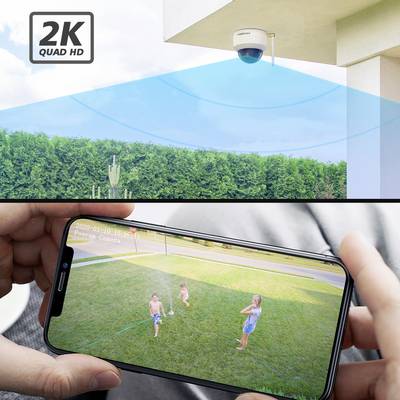 Überwachungsbild einer Sicherheitskamera, oben an einem Gebäude, das über eine App auf einem Smartphone überprüft wird, während Kinder im Garten spielen.