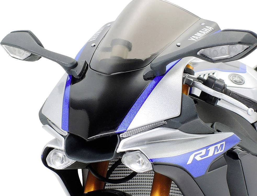 Ein silbernes und blaues Motorrad mit der Aufschrift 'R1M' auf der Verkleidung. Aerodynamische Details und klare Frontsicht.