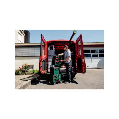 Ein Mann entlädt Werkzeugkoffer aus einem roten Lieferwagen auf einem Industriegelände.