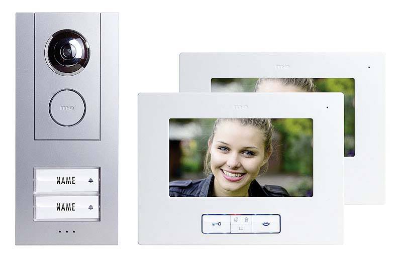 Video-Türsprechanlage mit Kamera und zwei Bildschirmen. Kamera zeigt eine lächelnde Person auf den Monitoren. Namensschilder unten.