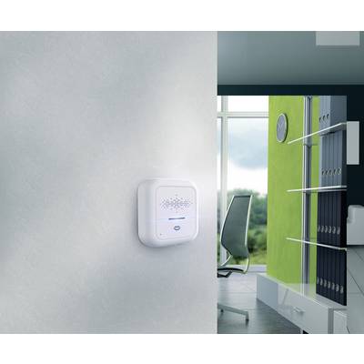 Ein modernes Büro mit einem Raumluftsensor an der Wand. Im Hintergrund steht ein Bürostuhl vor einem Fenster. Ordner sind im Regal.