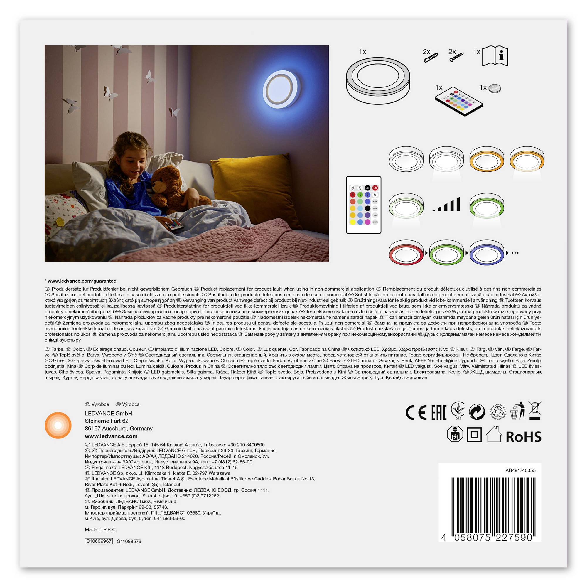 Ein Junge im Bett mit einem Spielzeug, beleuchtet von einem bunten Licht an der Wand. Neben ihm eine Fernbedienung mit Farboptionen. Verpackungsdesign vorne von Beleuchtungsprodukt.