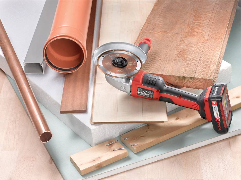 Verschiedene Baumaterialien wie Kupferrohr, Holz und Styropor liegen auf einem Tisch. Eine elektrische Säge ist neben ihnen platziert.