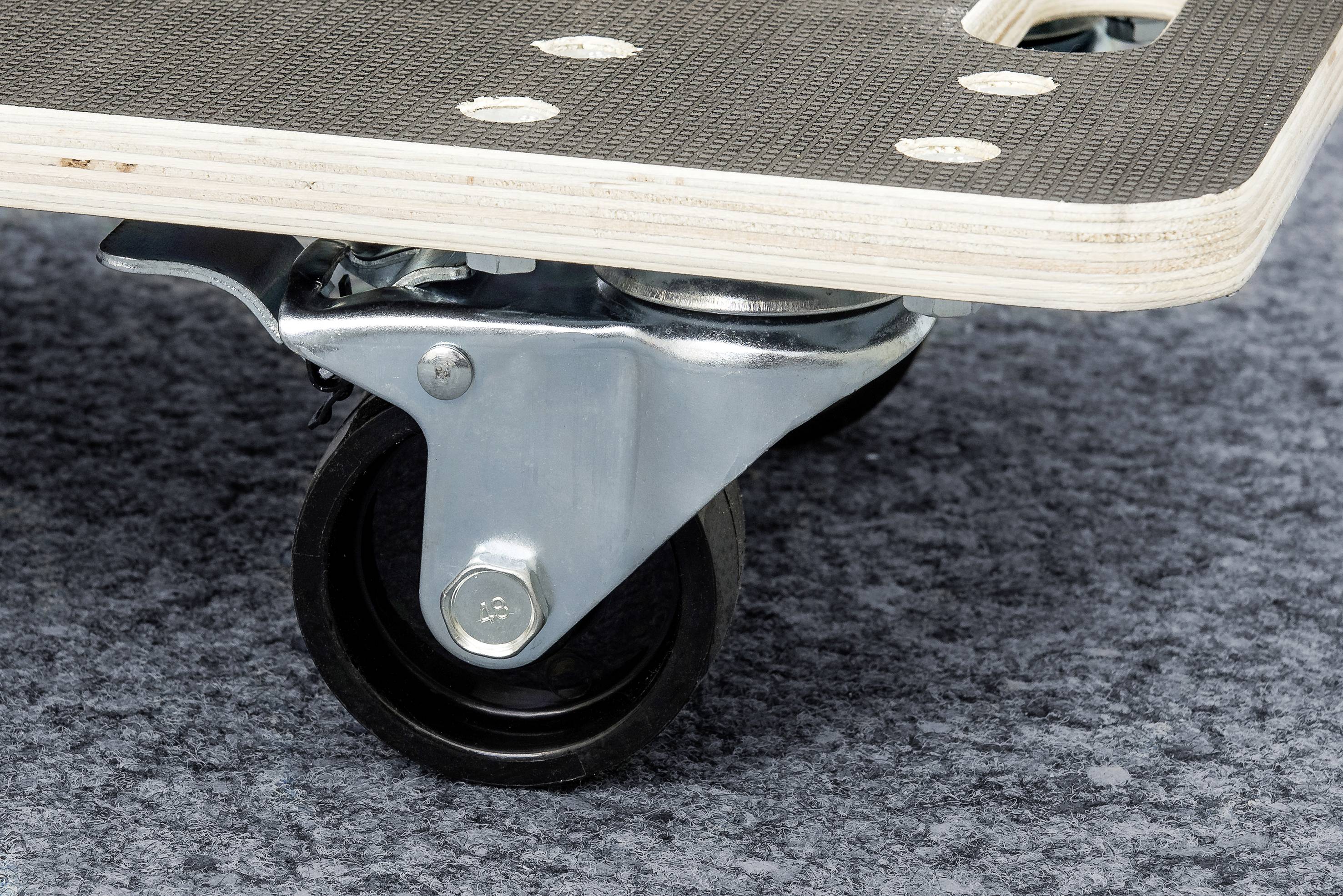 Nahaufnahme eines Möbelrollers mit schwarzem Rad und Metallhalterung auf grauem Teppich, zeigt Details der Konstruktion.