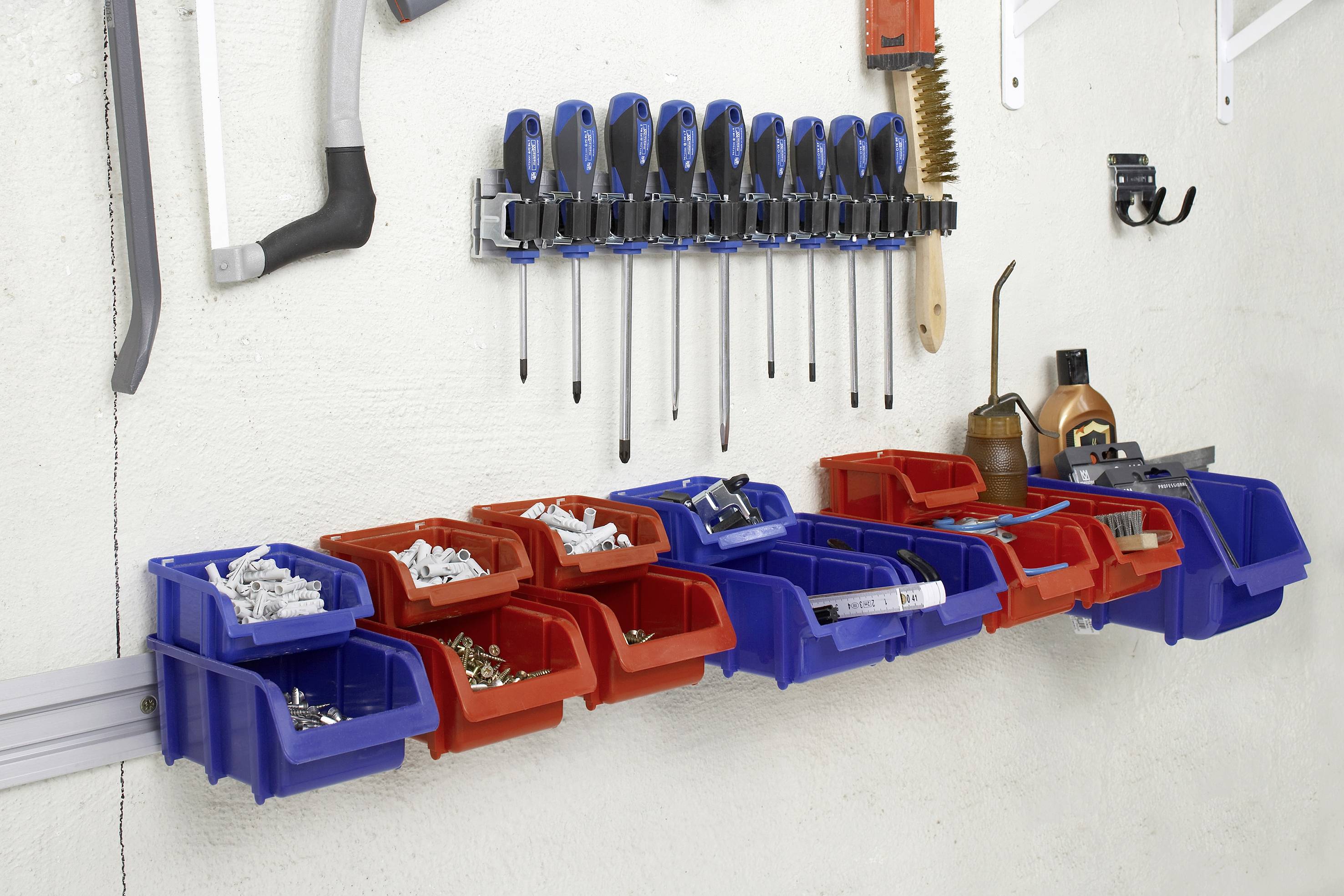Werkzeugwand mit Schraubendrehern oben, darunter rote und blaue Aufbewahrungsboxen mit Schrauben und Kleinteilen.