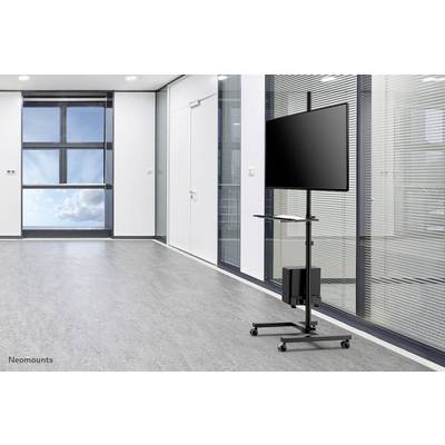 Ein leerer Konferenzraum mit großem Fenster und grauem Boden. Im Vordergrund steht ein mobiler Monitorständer mit einem Bildschirm.
