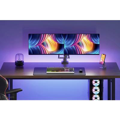 Ein Schreibtisch mit zwei leuchtend bunten Monitoren, einer RGB-Tastatur, einem Smartphone und einer Lampe, umgeben von blauer Hintergrundbeleuchtung.