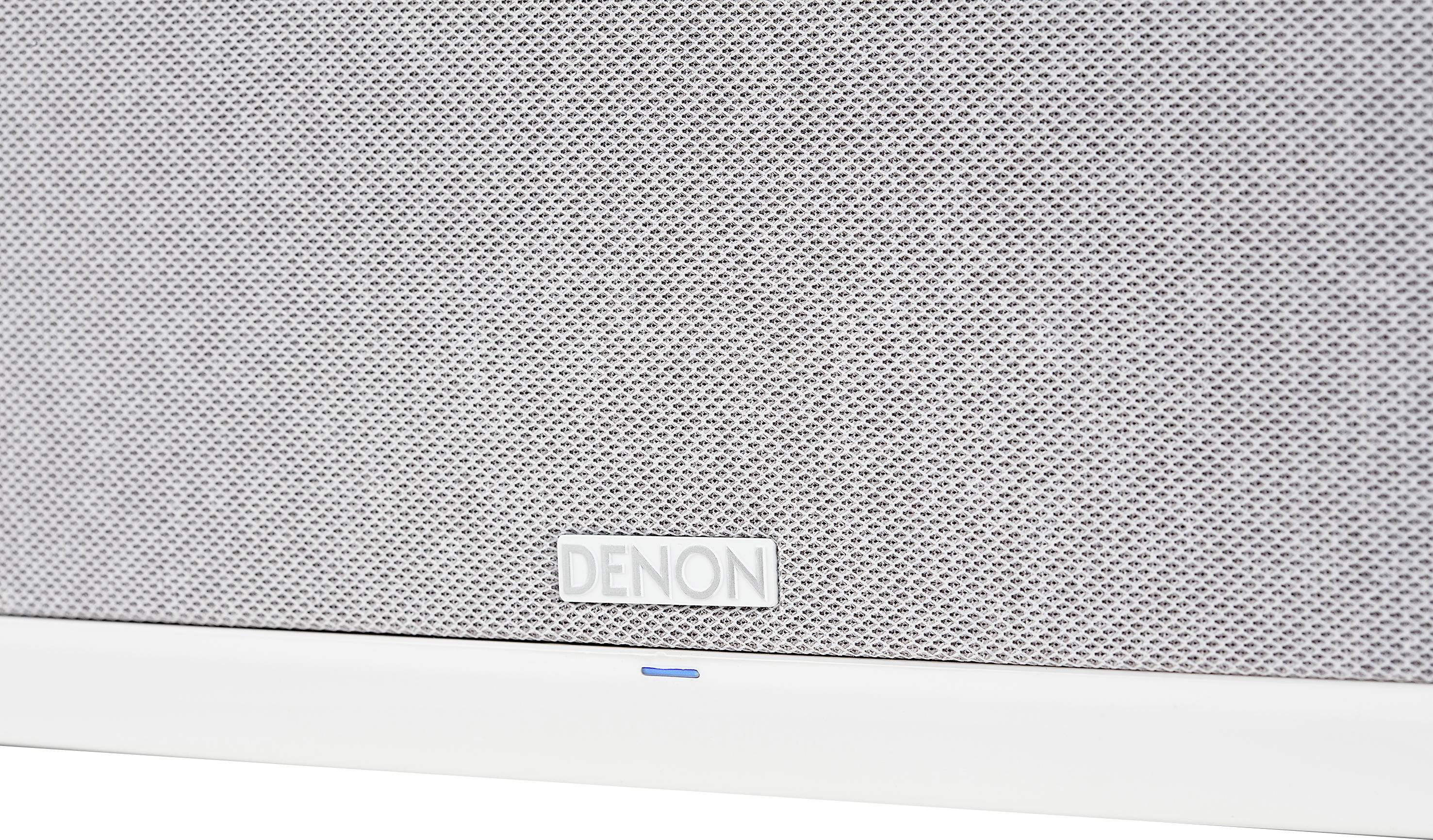 Nahaufnahme eines Lautsprechers mit grauem Gitter und der Marke 'Denon'. Eine blaue LED-Anzeige leuchtet am unteren Rand.