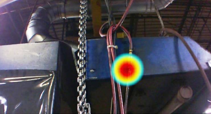 Industrieanlage mit wärmeempfindlichem Punkt, dargestellt durch farbige Wärmestrahlung in Rot und Gelb auf einem metallischen Hintergrund.