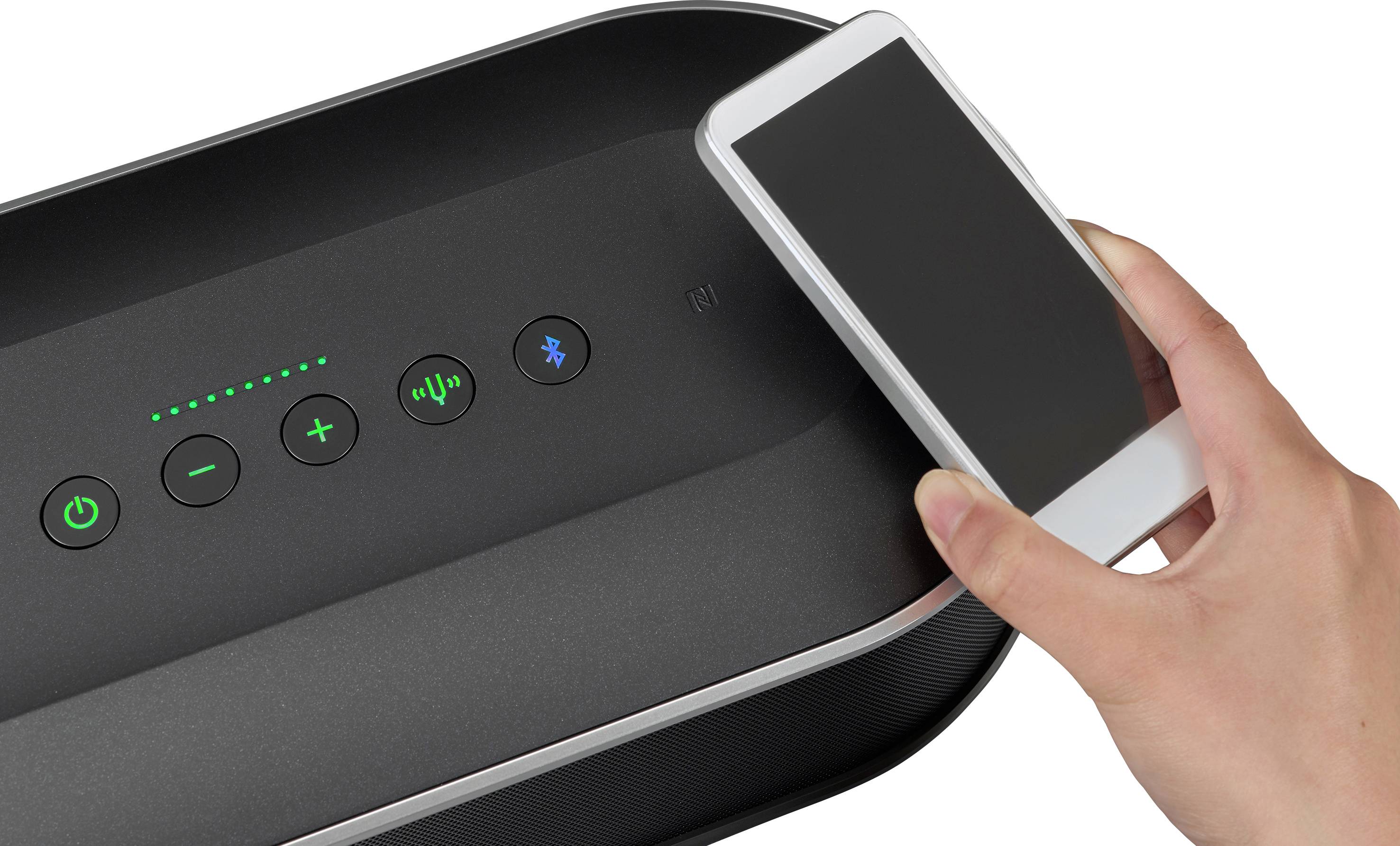 Eine Hand hält ein Smartphone über einen Lautsprecher zur drahtlosen Verbindung. Bedienelemente und Bluetooth-Symbol sichtbar.