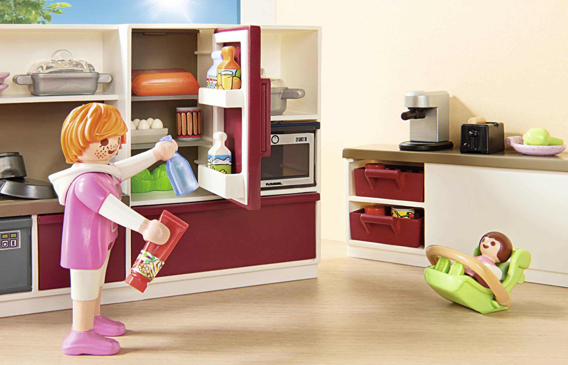 Kleines Kind spielt in der Spielküche, öffnet den Kühlschrank. Spielzeugmöbel und -gegenstände sind ebenfalls sichtbar.