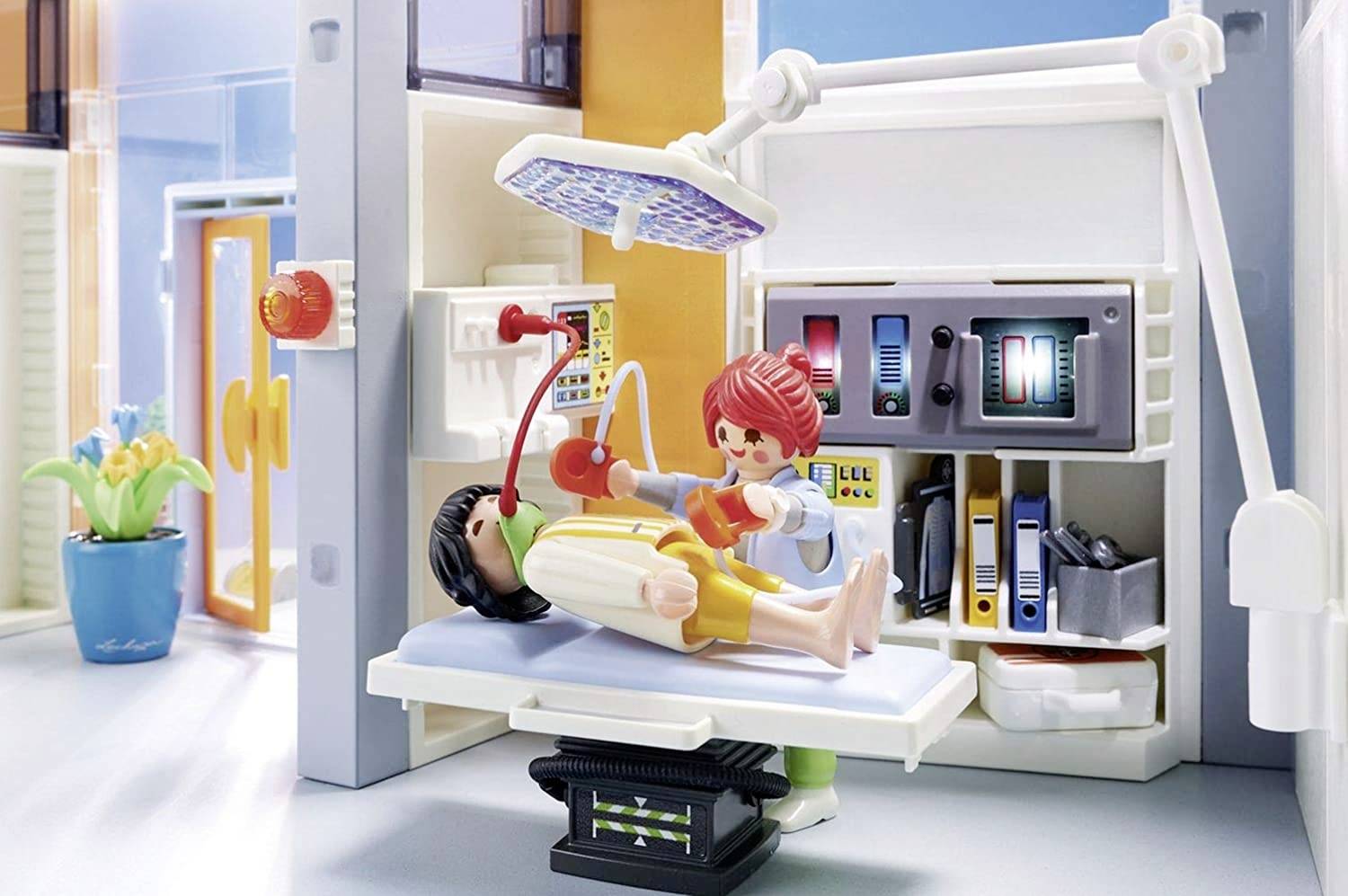 Eine Krankenhaus-Szene mit Playmobil-Figuren: Ein Arzt mit rotem Haar behandelt eine auf einem Untersuchungstisch liegende Figur.