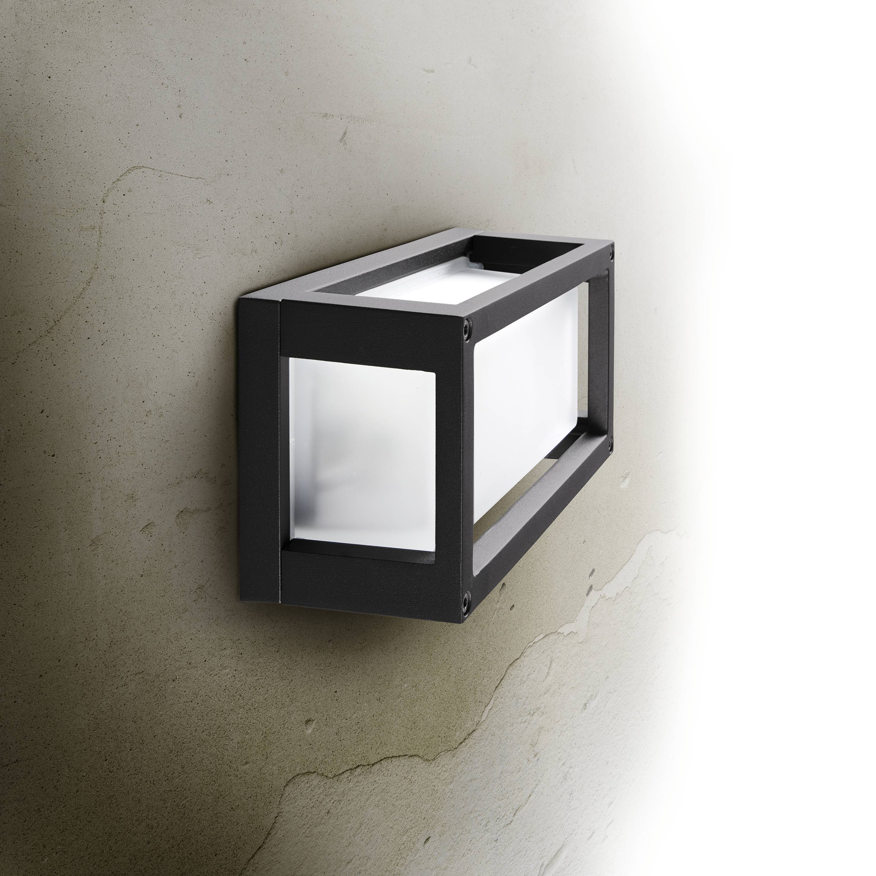 Eine rechteckige Wandleuchte mit schwarzem Rahmen und milchigem Glas, montiert an einer hellen, strukturierten Wand.