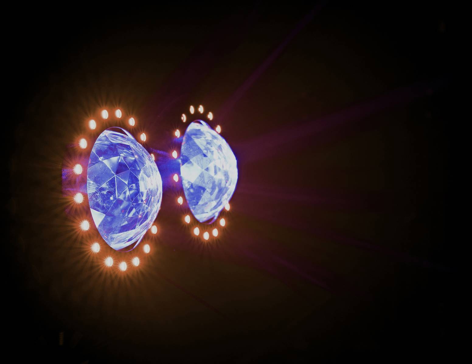 Zwei leuchtende Edelsteine, die von einem Ring aus kleinen Lichtern umgeben sind, erzeugen einen hellen, dekorativen Effekt im Dunkeln.