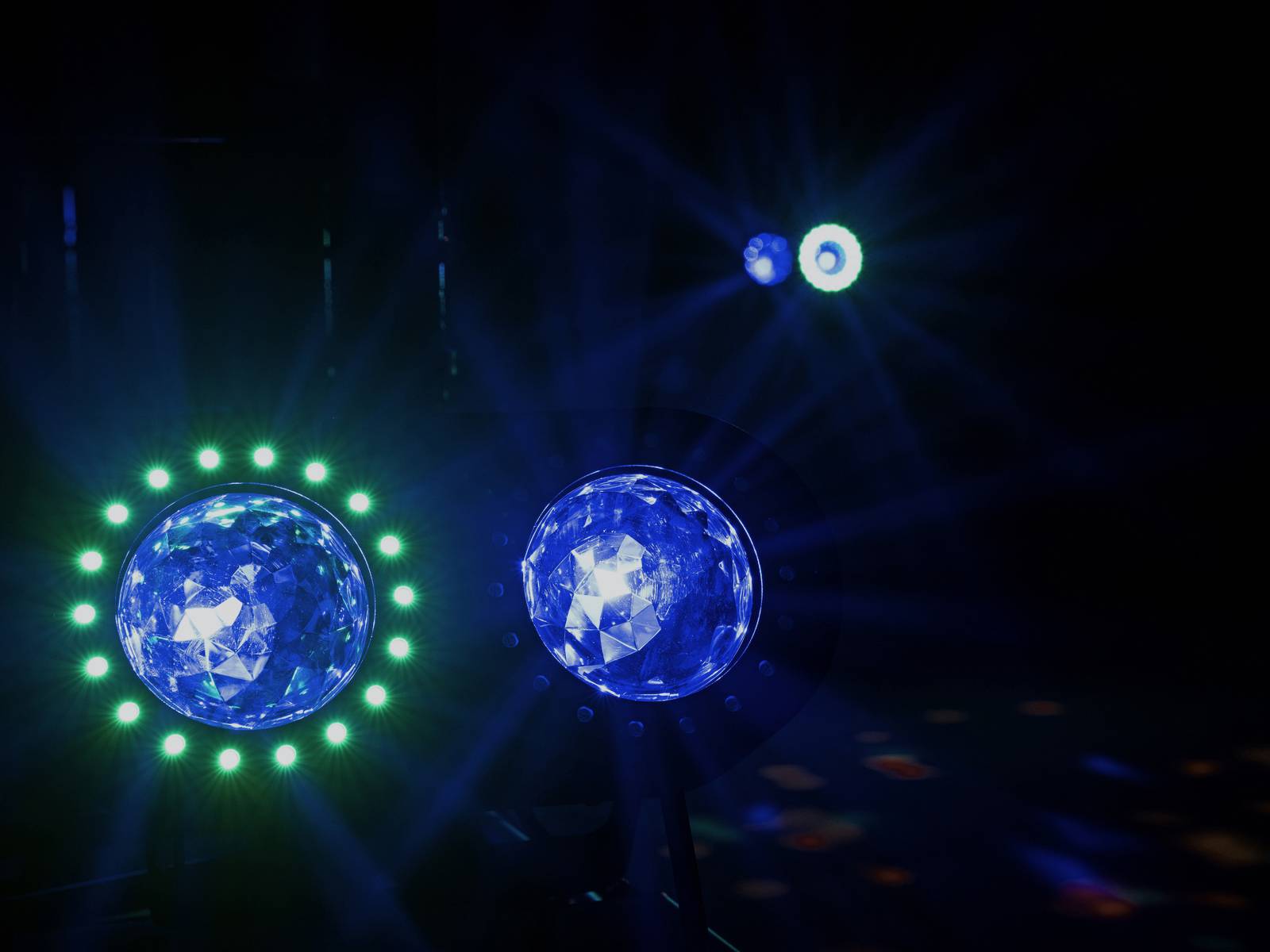 Blaue und grüne Bühnenlichter strahlen in einem dunklen Raum, erzeugen ein stimmungsvolles Ambiente für eine Veranstaltung oder Show.