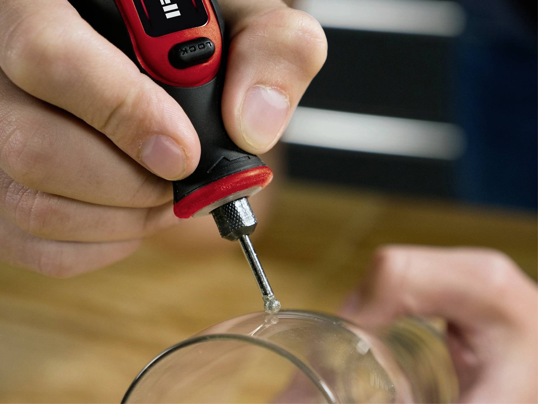 Eine Person verwendet einen roten und schwarzen Lötkolben, um eine kleine Reparatur an einem Glas durchzuführen.