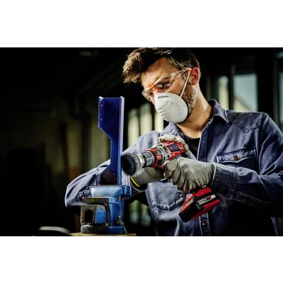 Ein Mann mit Schutzbrille und Maske schleift ein Metallstück mit einem Bohrschleifer in einer Werkstatt.